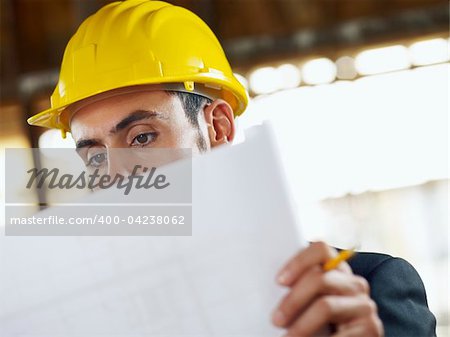 caucasian male architect examining blueprints. Horizontal shape, head and shoulders, front view, copy space