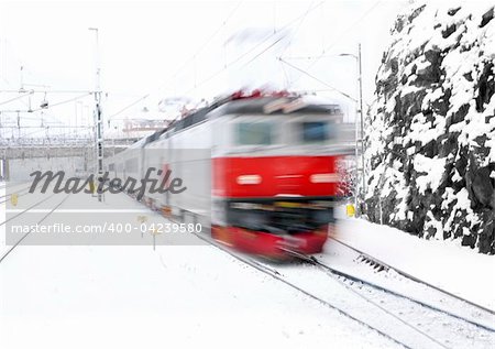 Red train in blurred motion approaching a station