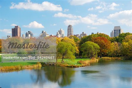 New York City Central Park in Autumn with Manhattan skyscrapers and colorful trees over lake with reflection.