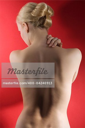 fashion elegant shot of blond woman with nude shulder and hair stylish taking pose on red background
