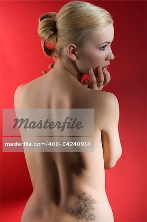 fashion elegant shot of blond naked woman with hair stylish taking pose on red background