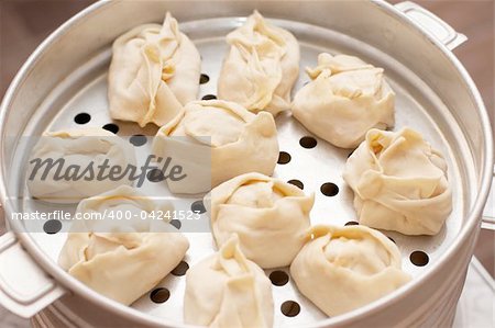 Uncooked oriental dumplings on metal steam cooker