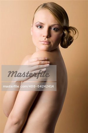 portrait of a naked woman on sepia background color with hair style looking in camera