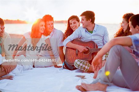 Homme jouant de la musique pour les amis sur la plage