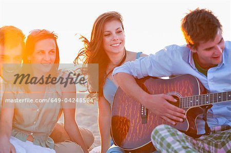 Man playing music for friends on beach