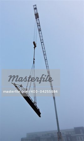 Photograph of a construction crane taken during a foggy morning