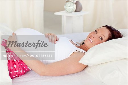 Radiant pregnant woman resting n her bed in the bedroom at home