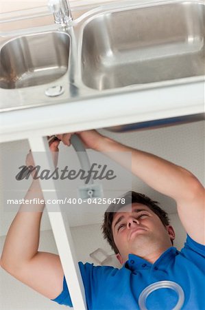 plumber making efforts to repair a sink lying on the floor in the kitchen