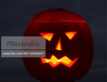 Halloween pumpkin on grey cloudy background lit by candles