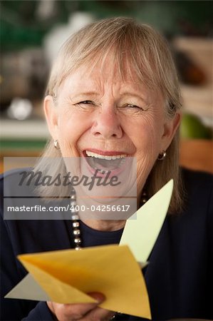 Senior woman at home reading greeting card