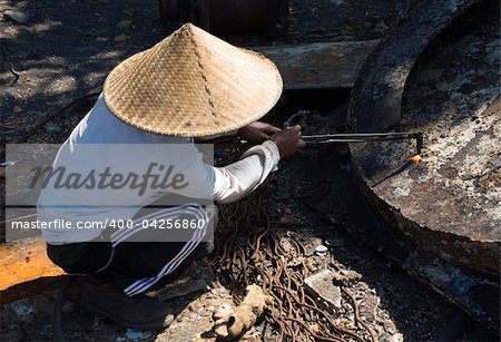 Indonesian worker cutting metal using a cutting torch