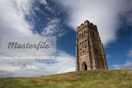 Tourists exploring the ruins of St. Michael's Tower at the top of glastonbury tor in somerest england