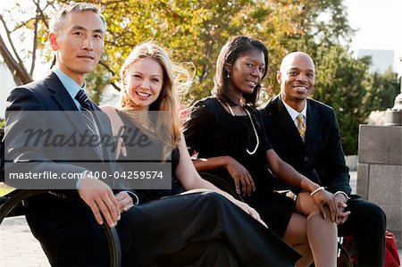 A multicultural business team on a bench in a park