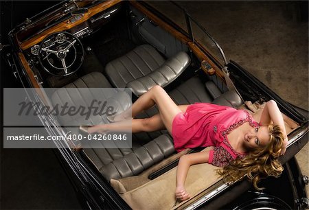 pretty girl in a pink mini dress in an old car