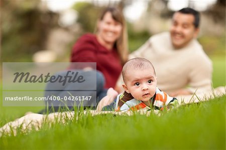 Happy Crawling Baby Boy and Mixed Race Parents Playing in the Park.