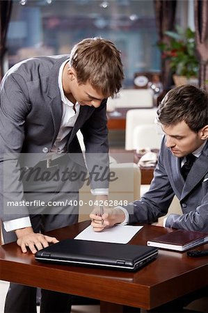 Two businessmen at restaurant consider the document