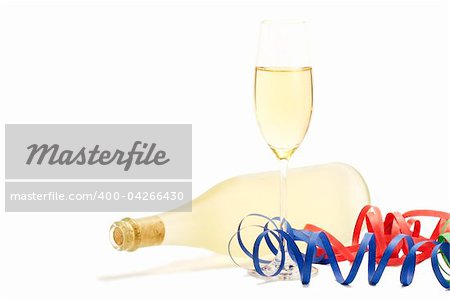 glass with champagne with streamer in front of a dull prosecco bottle on white background