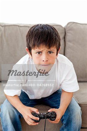 Cute boy playing video games sitting on the sofa at home