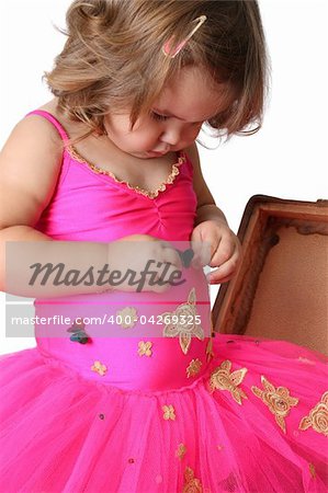 Little girl with wearing a bright pink tutu standing in an old suitcase