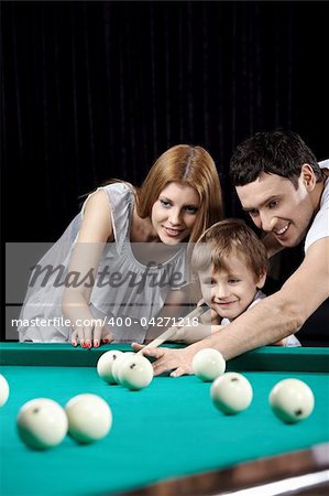 The young couple and the child plays billiards