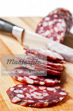 Salami sliced on chopping board isolated on white