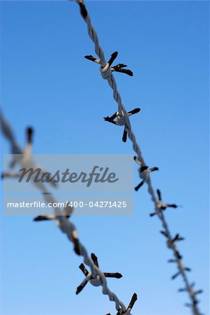 Close-up of a barbed wire over the blue sky outdoors.