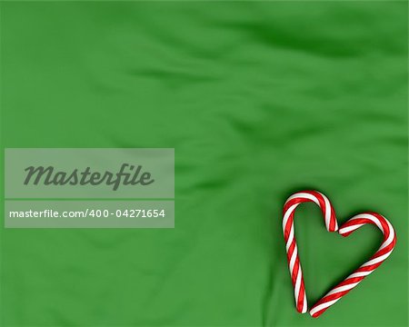 Heart made from christmas candies on green fabric background