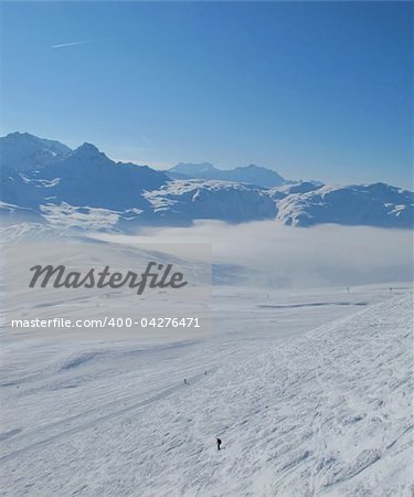 Lone skier. French alp mountains and clouds in valleys. Skiing Les Contamines, French alps