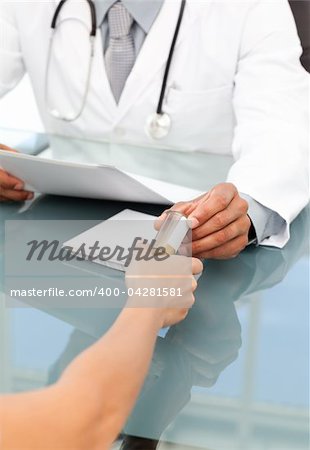 Close up of a doctor giving medicine to his patient during an appointment in his office