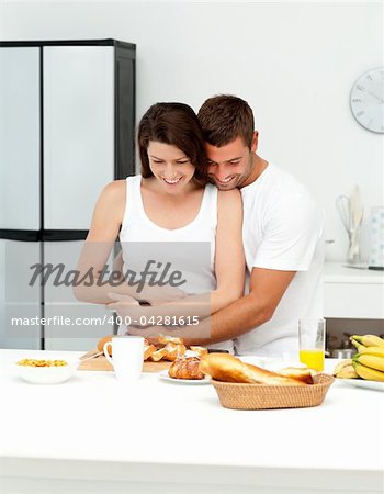 Happy couple hugging while preparing their breakfast together in the kitchen