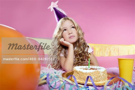 bored little blond girl in a birthday party with cake and candle on pink background