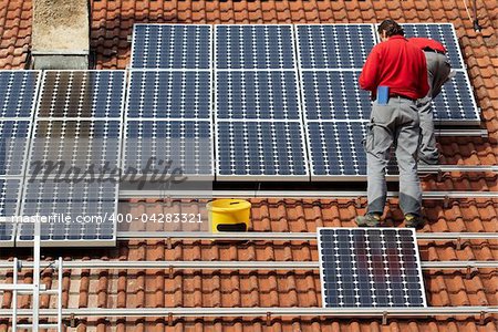 worker installing solar panels on roof