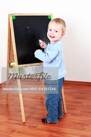 Adorable boy playing with chalkboard