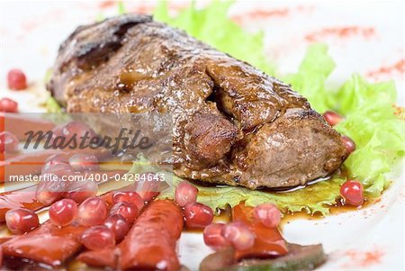 Roasted beef steak with pomegranate closeup at plate