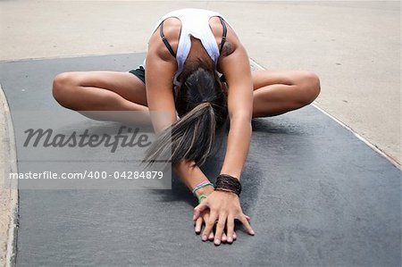 young hispanic female stretching outside before a run