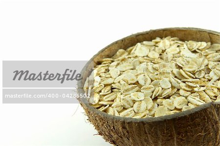 Wheat flakes in a coconut shell bowl isolated on white background