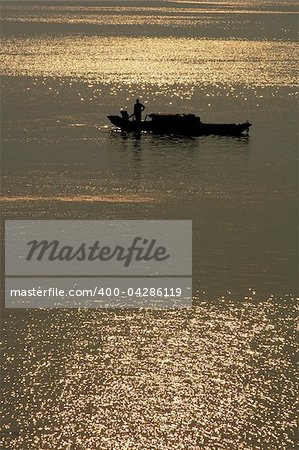 Silhouette of a filshing boat in lake at sunset