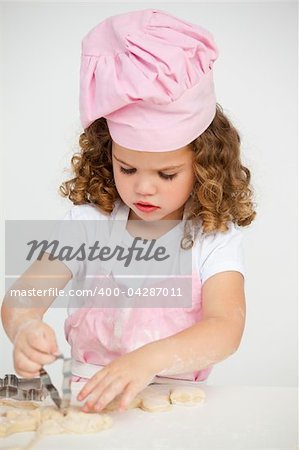 Cute little girl making biscuit at a table in the kitchen