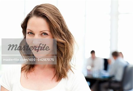 Relaxed businesswoman standing in front of her team while working at a table