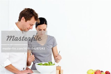 Active couple preparing a salad for lunch in the kitchen