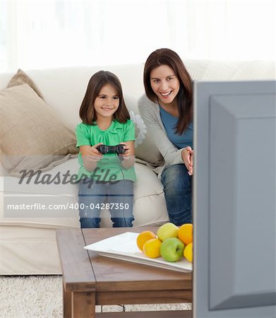 Pretty mom encouraging her daughter playing video games in the living room