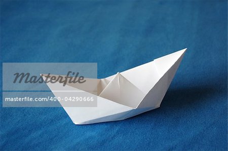 origami paper boat isolated on blue water