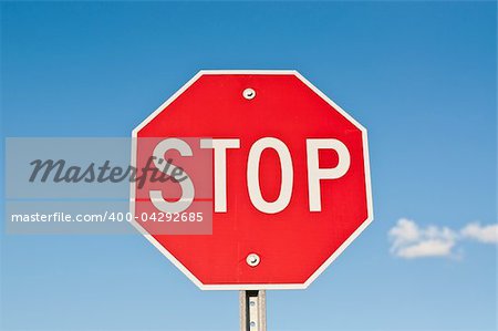 A red octagonal stop sign with blue sky and clouds in the background.