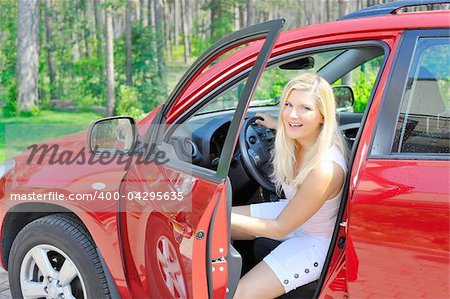 beautiful woman driver in red shiny car opens the door