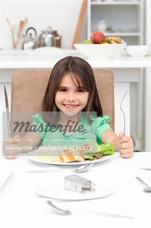 Adorable llittle girl holding forks to eat pasta and salad in the kitchen