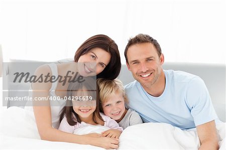 Portrait of a happy family sitting on the bed in the morning