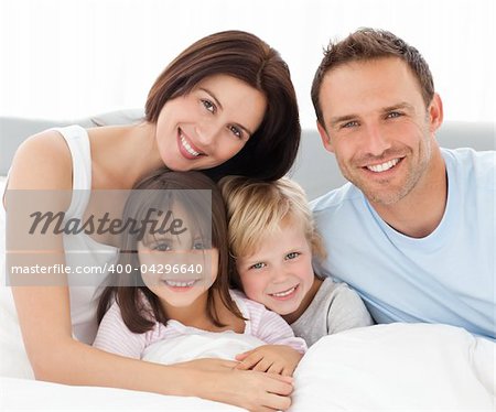 Portrait of a happy family sitting on the bed in the morning