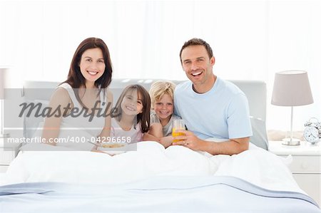 Happy family having breakfast together on the bed at home