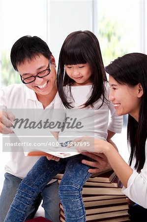 Happy asian family studing together. Parent helping daughter  reading book