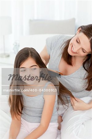 Woman brushing her daughter hair at home